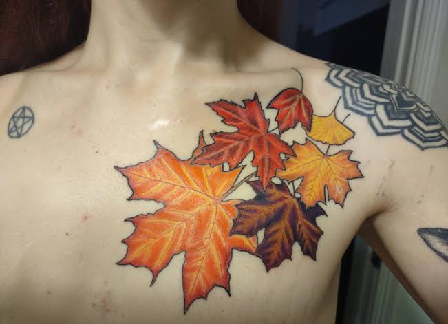 Colorful maple leaves in red, orange, yellow, and purple sweep across the collarbone and upper chest.