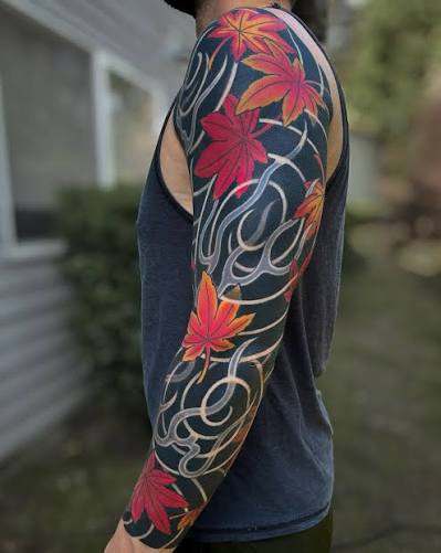 Red and orange maple leaves with navy shading and curling white lines form a full arm sleeve.