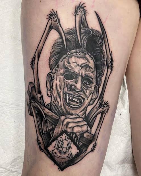 Black and gray thigh tattoo of a Deadite with dark eye sockets, bared teeth, and clawed hands.