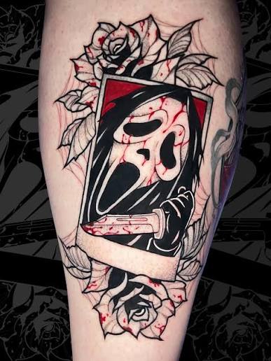 Ghostface tattoo inside a tilted frame, surrounded by roses and a knife on the calf.