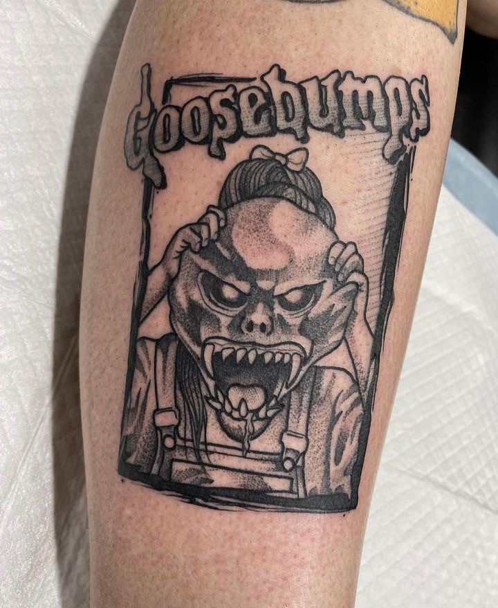 Black and gray leg tattoo of a fanged monster beneath the Goosebumps logo.