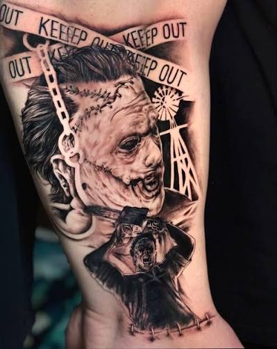 Black and gray Leatherface tattoo with a stitched mask, keep out tape, and a small chainsaw scene.