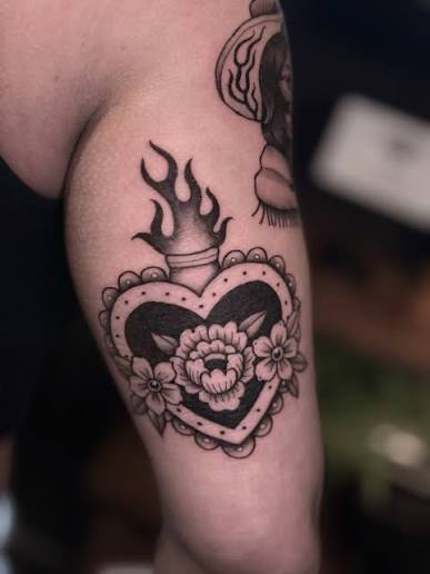 Flaming black heart surrounded by flowers and tiny pearl details on the upper arm
