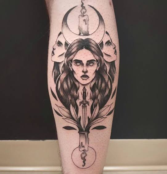Three goddess faces with a candle, crescent moon, and dagger in a calf tattoo