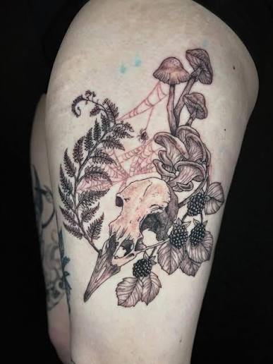 Bird skull surrounded by curling mushrooms and ferns on the upper arm