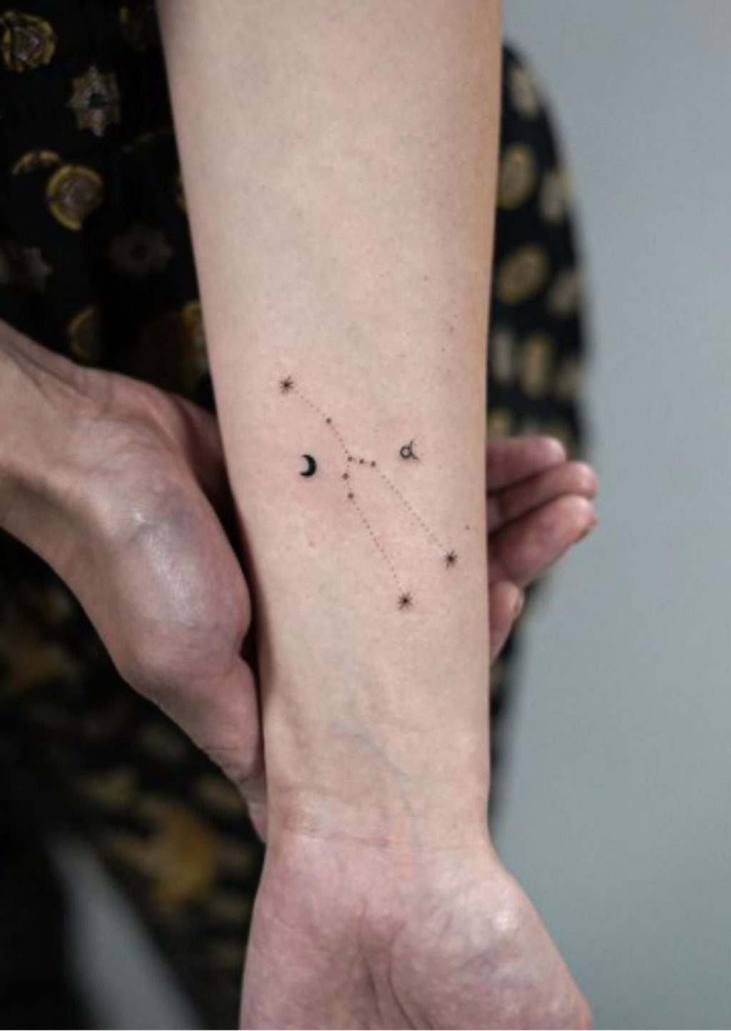 Small crescent moon and stars connected by dotted lines on the inner forearm