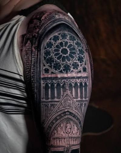 Carved church portal tattoo with a circular stained glass motif wrapping the shoulder