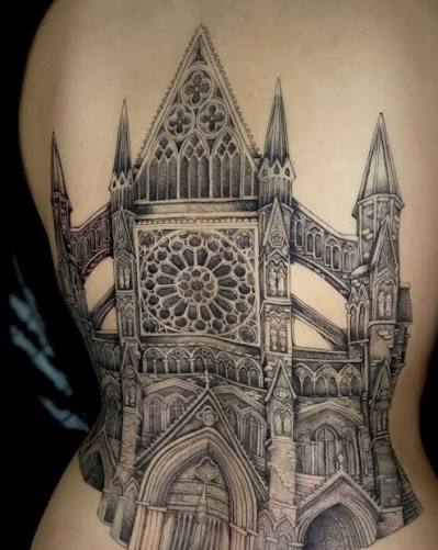 Large Gothic cathedral facade tattoo with layered arches, carved tracery, and tall towers on the side
