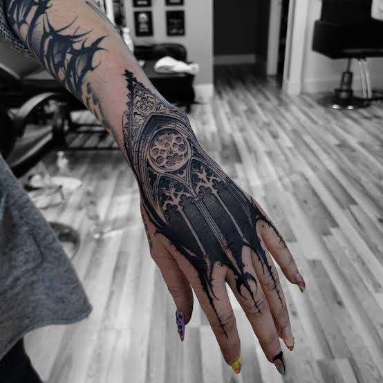 Dark rose window tattoo spreading across the hand, wrist, and fingers