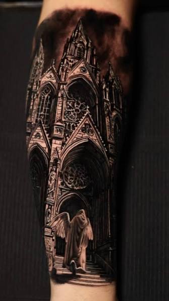 Winged angel beneath a soaring Gothic cathedral doorway in a blackwork forearm tattoo