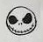 Round skull face with dark eyes and a stitched grin.
