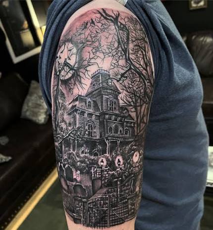 Black and grey mansion half sleeve tattoo shows bare branches, a shadowy house, iron gate, and tombstones.