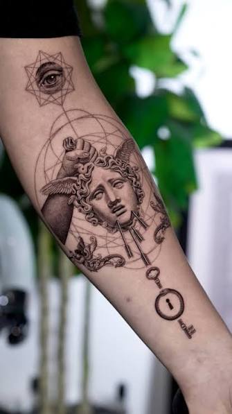 Geometric Medusa forearm tattoo with snake curls, fine circles, an eye above her head, and a key near the wrist.