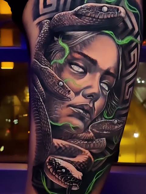 Neon green wisps surround a haunted Medusa face with blank white eyes and finely scaled snakes on the arm.