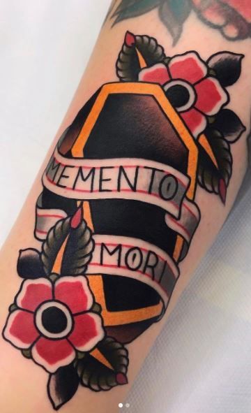 Traditional black coffin tattoo with bright orange trim, pink flowers, thick outlines, and a memento mori ribbon.