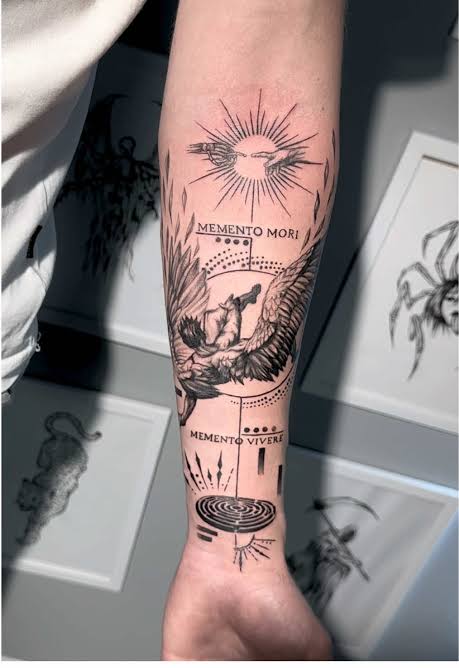 Winged falling figure on the forearm with memento mori and memento vivere text, a sun, and a circular maze.