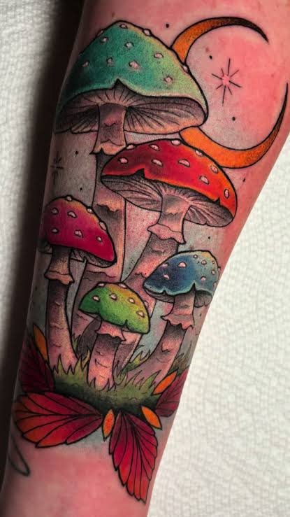 Crescent moon, red moth, and spotted mushrooms arranged in a tall forearm tattoo.
