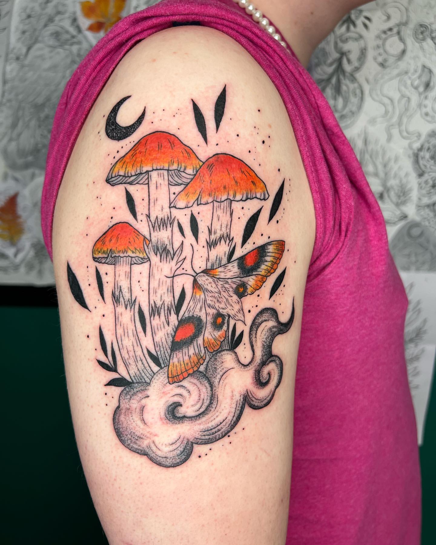Orange mushrooms, a hovering moth, crescent moon, and smoky swirls across the upper arm.