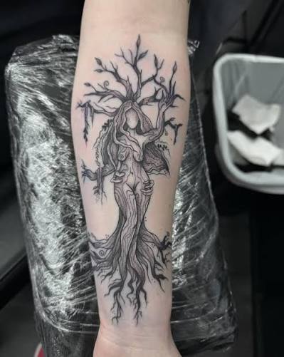 Anatomical heart joined to a bare tree, with branches and roots along the inner forearm