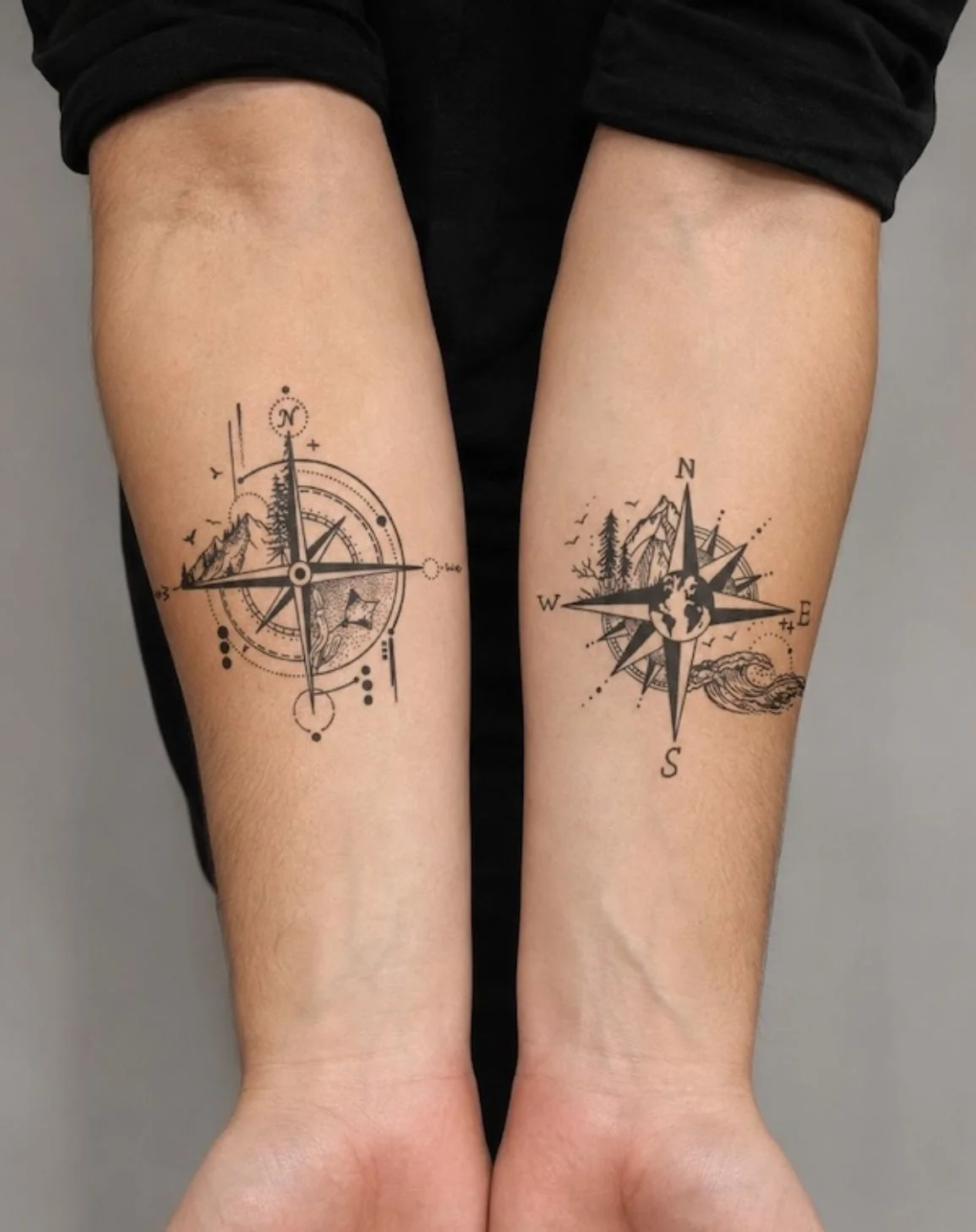 Compass rose tattoos with mountains and pine trees on two inner forearms