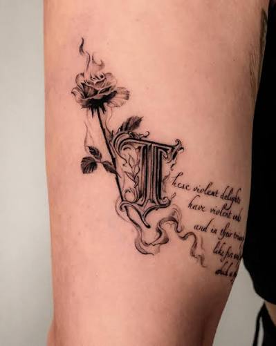 Ornate gothic initial beside a smoky rose and handwritten verse on the thigh