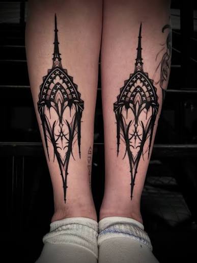 Paired gothic cathedral windows with sharp spires, stars, and fine tracery on both forearms