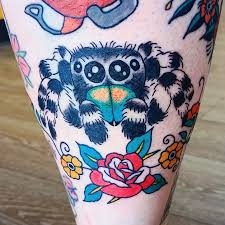 Traditional jumping spider tattoo with bold color and rose accents on the shin.