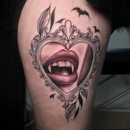 Ornate gothic heart framing sharp vampire fangs and tiny bats on the upper thigh