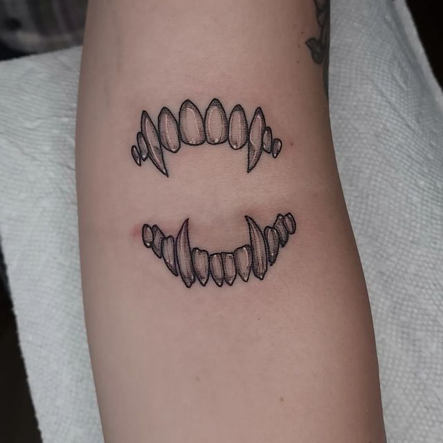 Open vampire bite drawn in fine black lines with grainy shading on the inner forearm