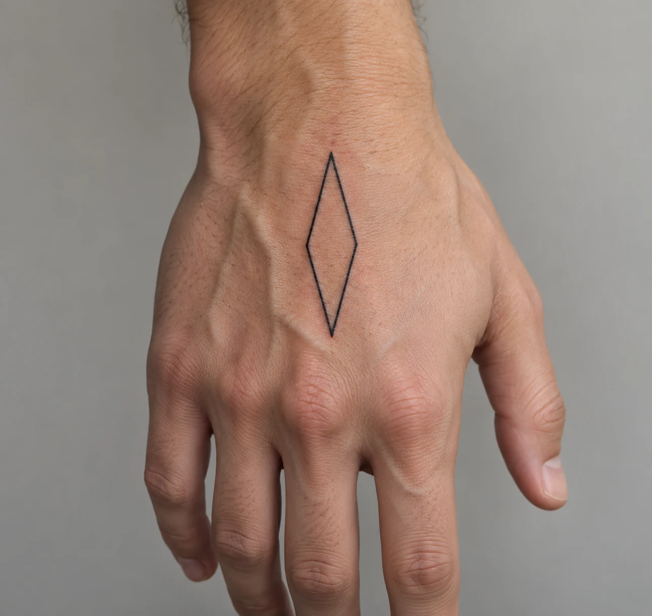 Elongated black diamond outline tattoo centered on the back of a hand.