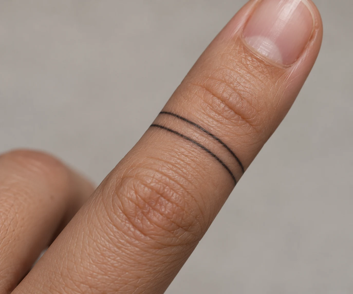 Two short parallel black lines forming an open tattoo band across the top of a finger.